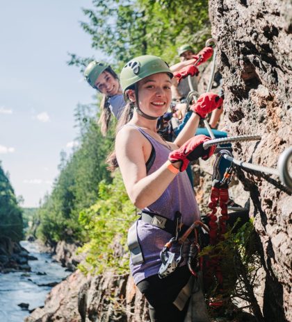 deux filles souriantes portant des casques grimpant sur des rochers en amont de la rivière coulonge